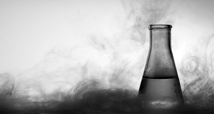 black and white photo of glass laboratory beaker with vapor swirling around