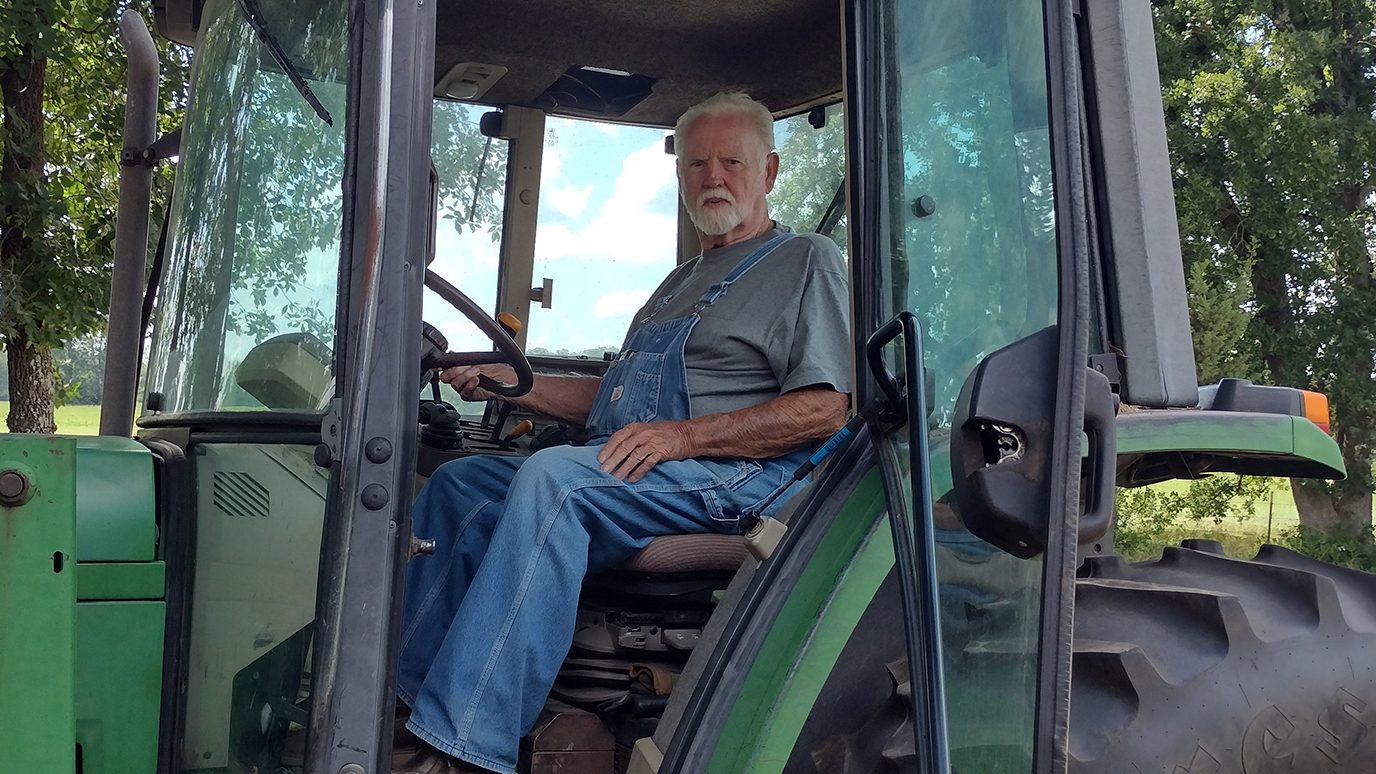 Stage IV colon cancer survivor Gene Jones on a tractor at his farm