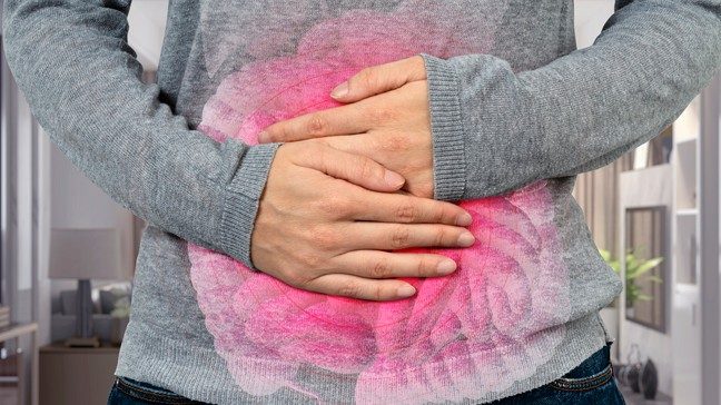 Waist view of woman in gray sweater holding abdomen in pain with internal organs superimposed in pink
